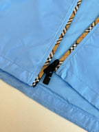 Blue jacket zip placket detail with black zipper tape and striped trim