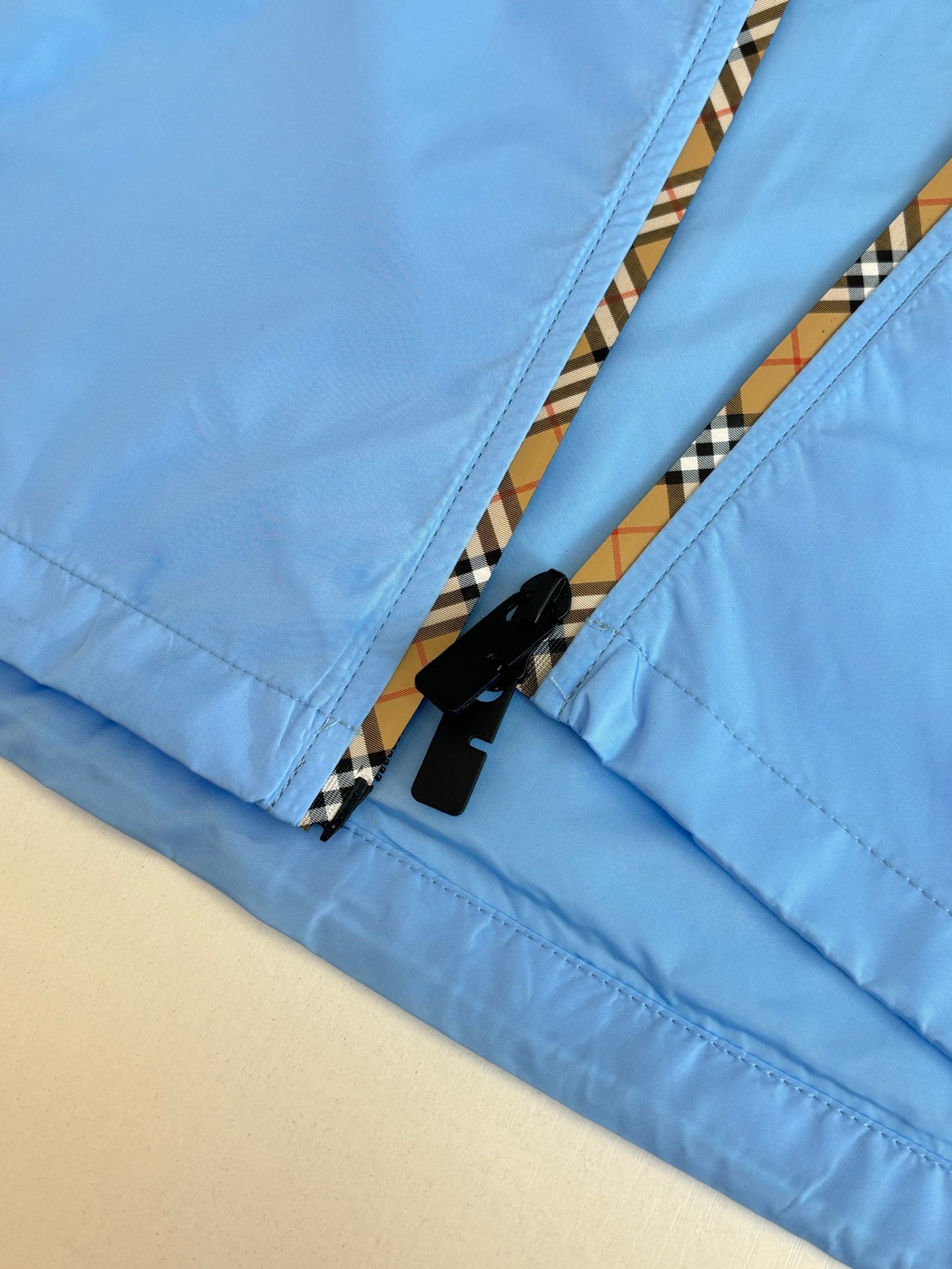 Blue jacket zip placket detail with black zipper tape and striped trim