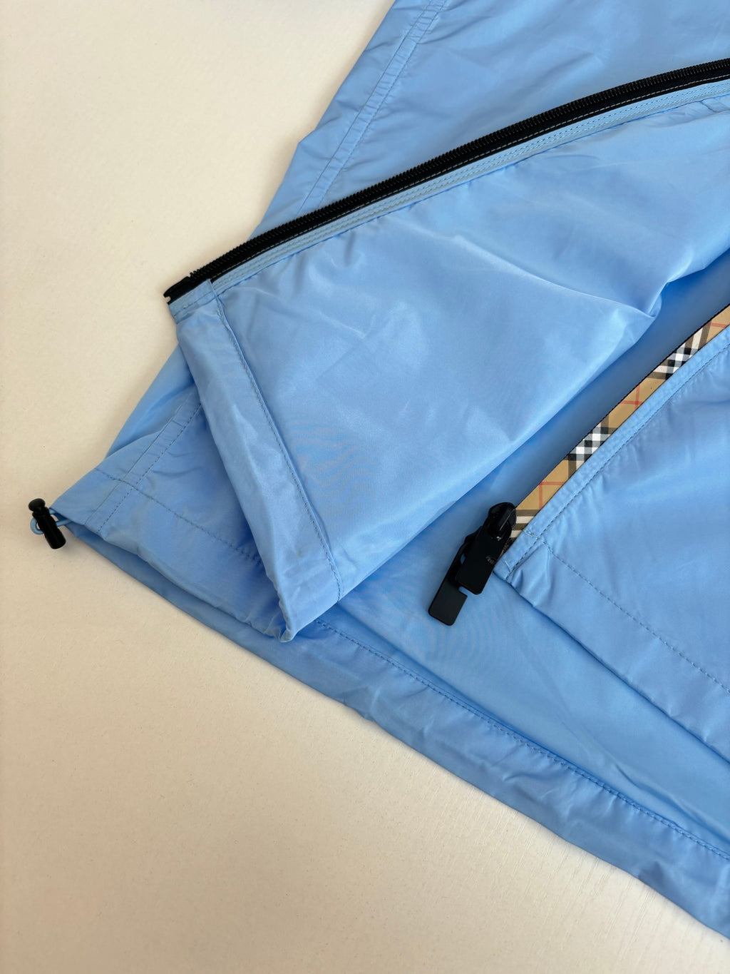 Blue jacket folded flat with black zipper edge and pull tabs