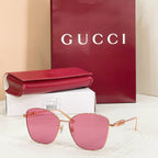 Sunglasses with gold metal frame and pink tinted lenses; cat-eye style