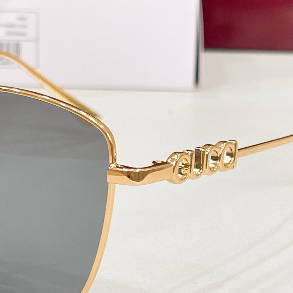 Gold sunglasses temple with Gucci lettering and dark lens frame edge