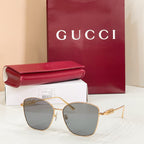 Sunglasses with gold metal frame and dark gray tinted lenses; cat-eye shape