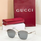 Sunglasses with gold metal frame and light blue tinted lenses; sleek cat-eye design