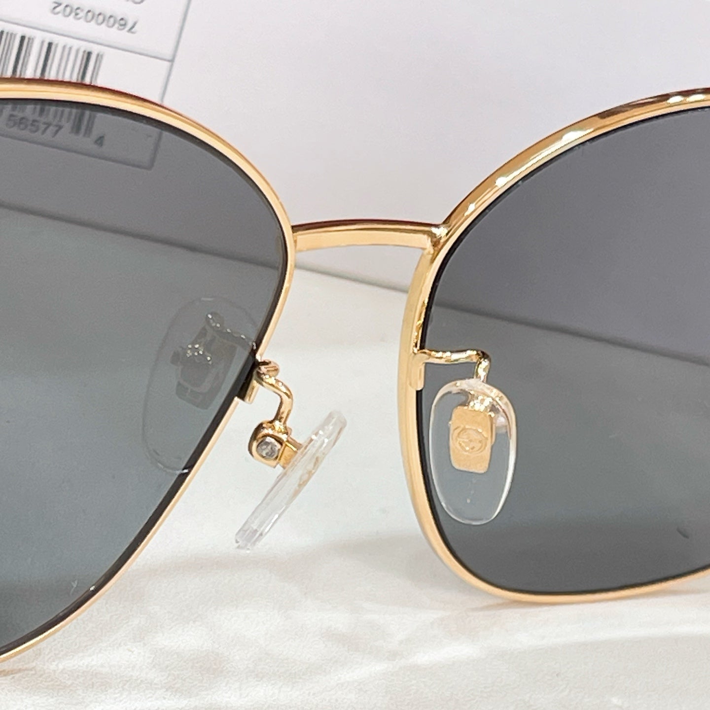 Sunglasses close-up with gold rim and dark lenses; bridge and logo detail