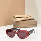 Bvlgari round sunglasses with burgundy frame and dark lenses, gold-toned charm on temple.