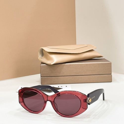 Bvlgari round sunglasses with burgundy frame and dark lenses, gold-toned charm on temple.