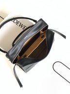 Loewe black leather bag open with tan interior lining and crossbody strap