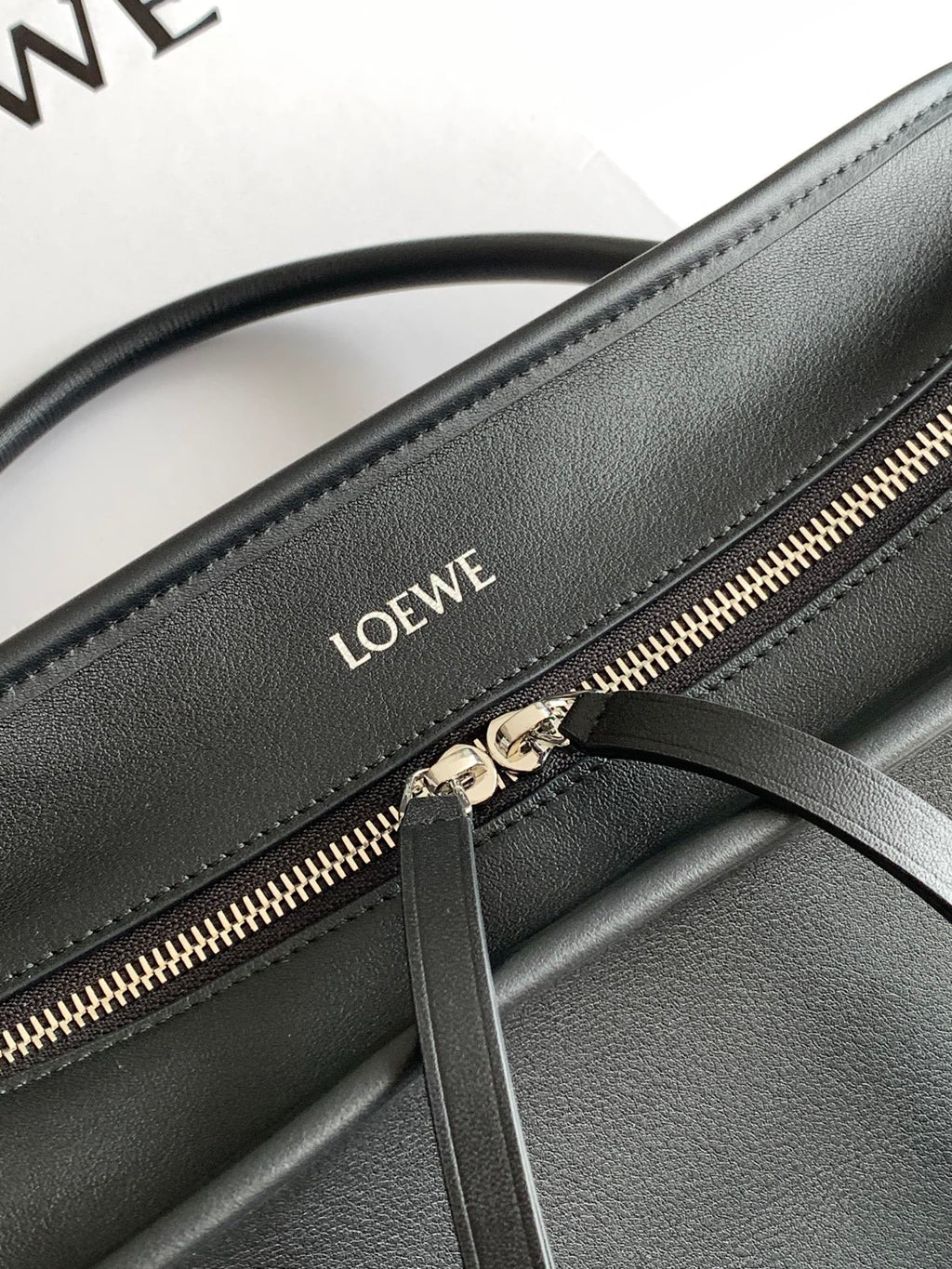 Black leather bag zipper detail with Loewe logo and gold-tone zipper teeth