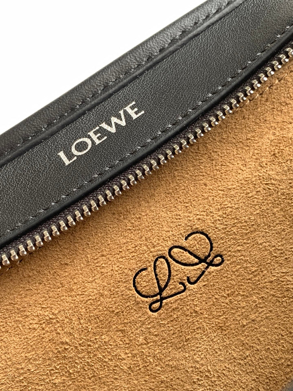 Black leather bag interior close-up with Loewe logo stamp near zip pocket