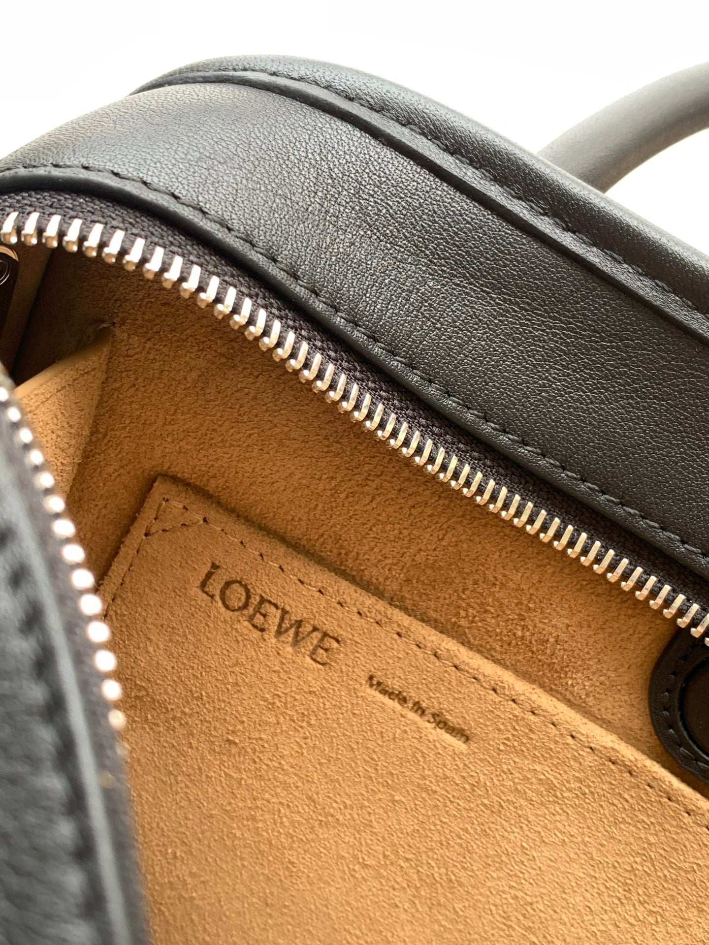 Black leather bag interior close-up with gold zipper and Loewe stamp