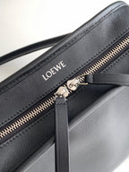 Black leather bag close-up: gold zipper and Loewe logo on front panel