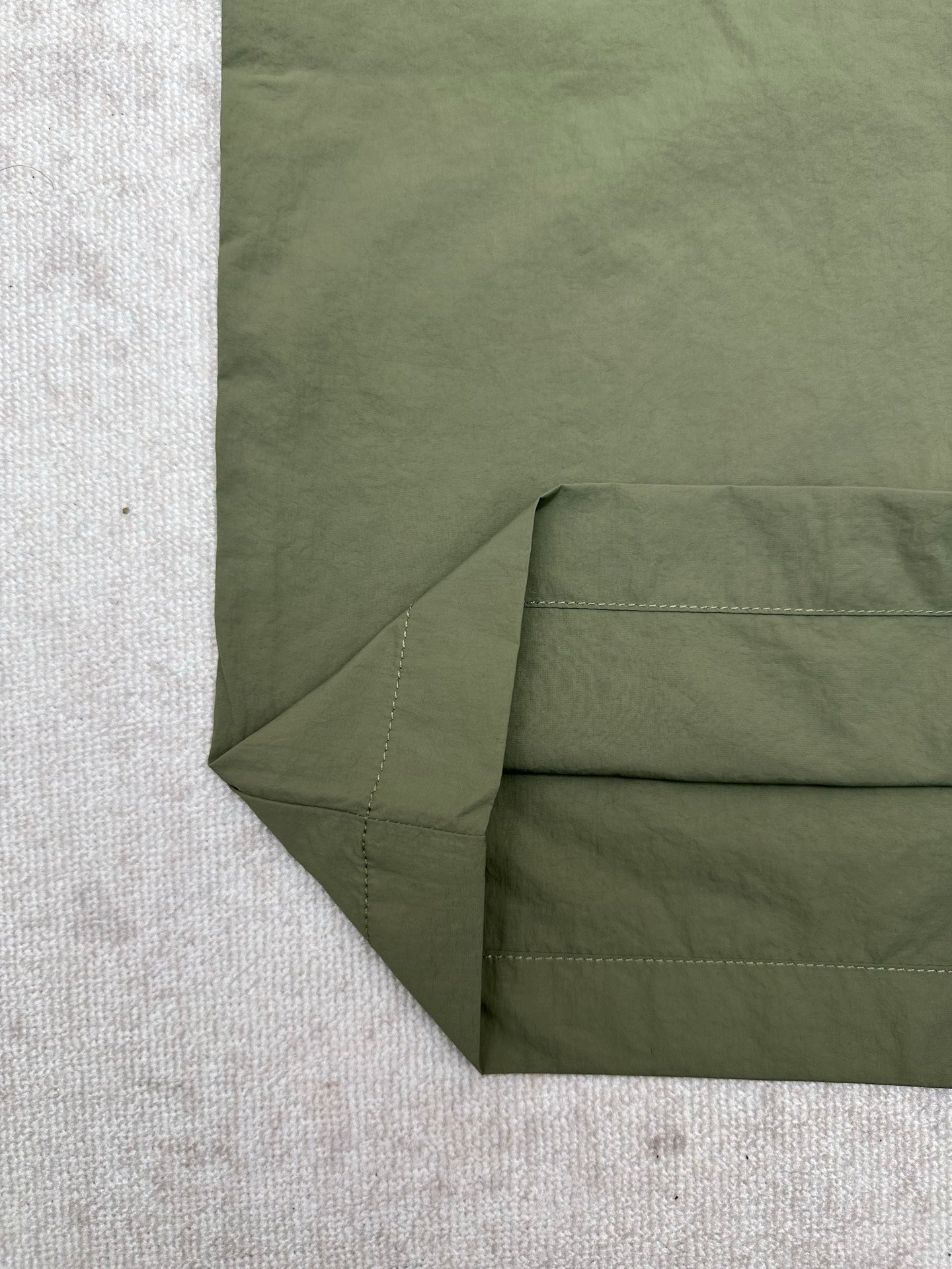 Olive green Louis Vuitton pants fabric close-up at folded hem and side seam