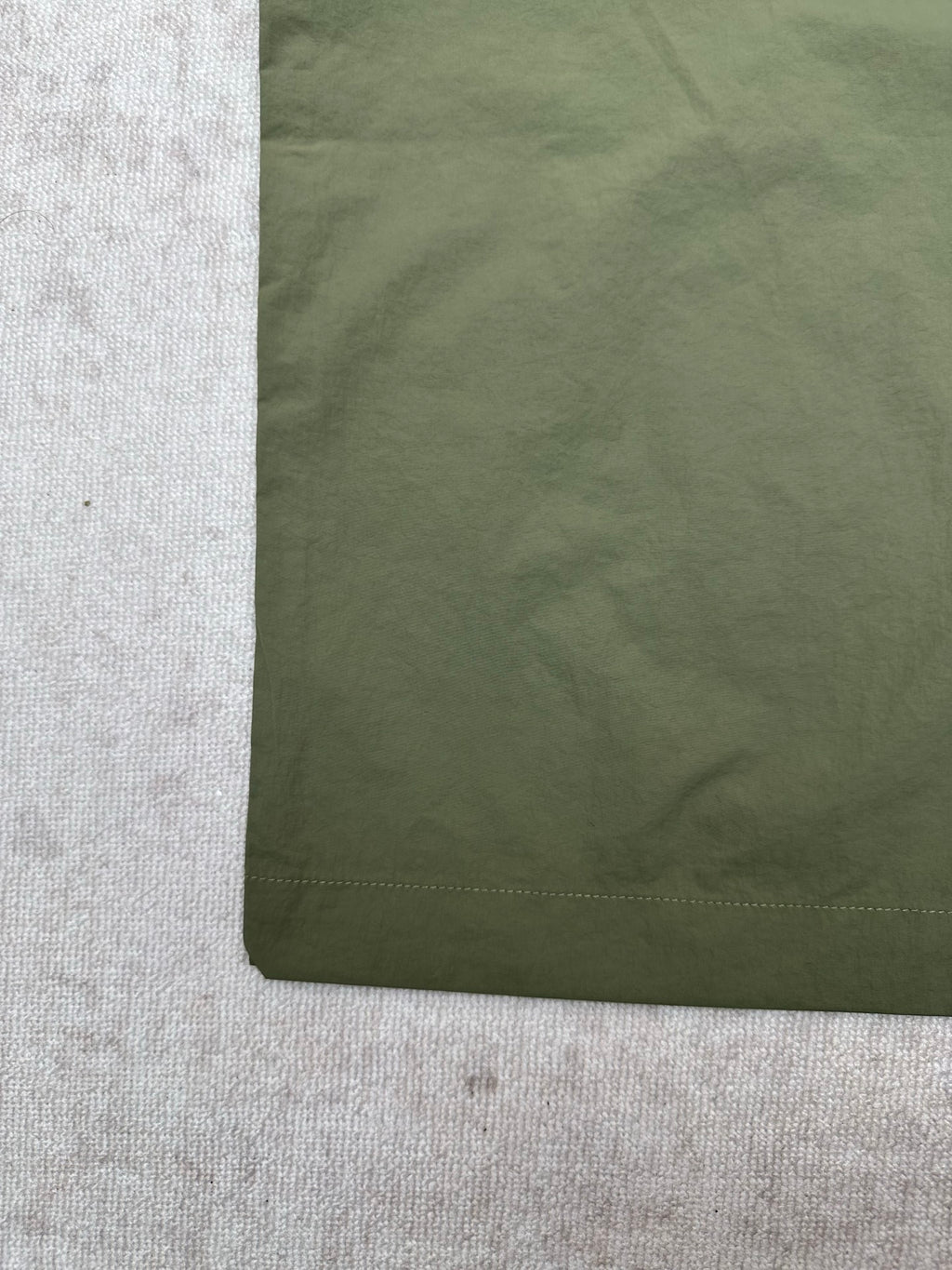 Olive green Louis Vuitton pants fabric close-up with stitched hem