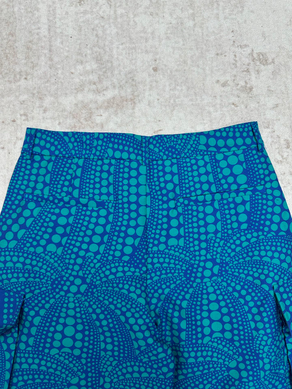 Blue shorts with teal circular pattern and pleated front panel