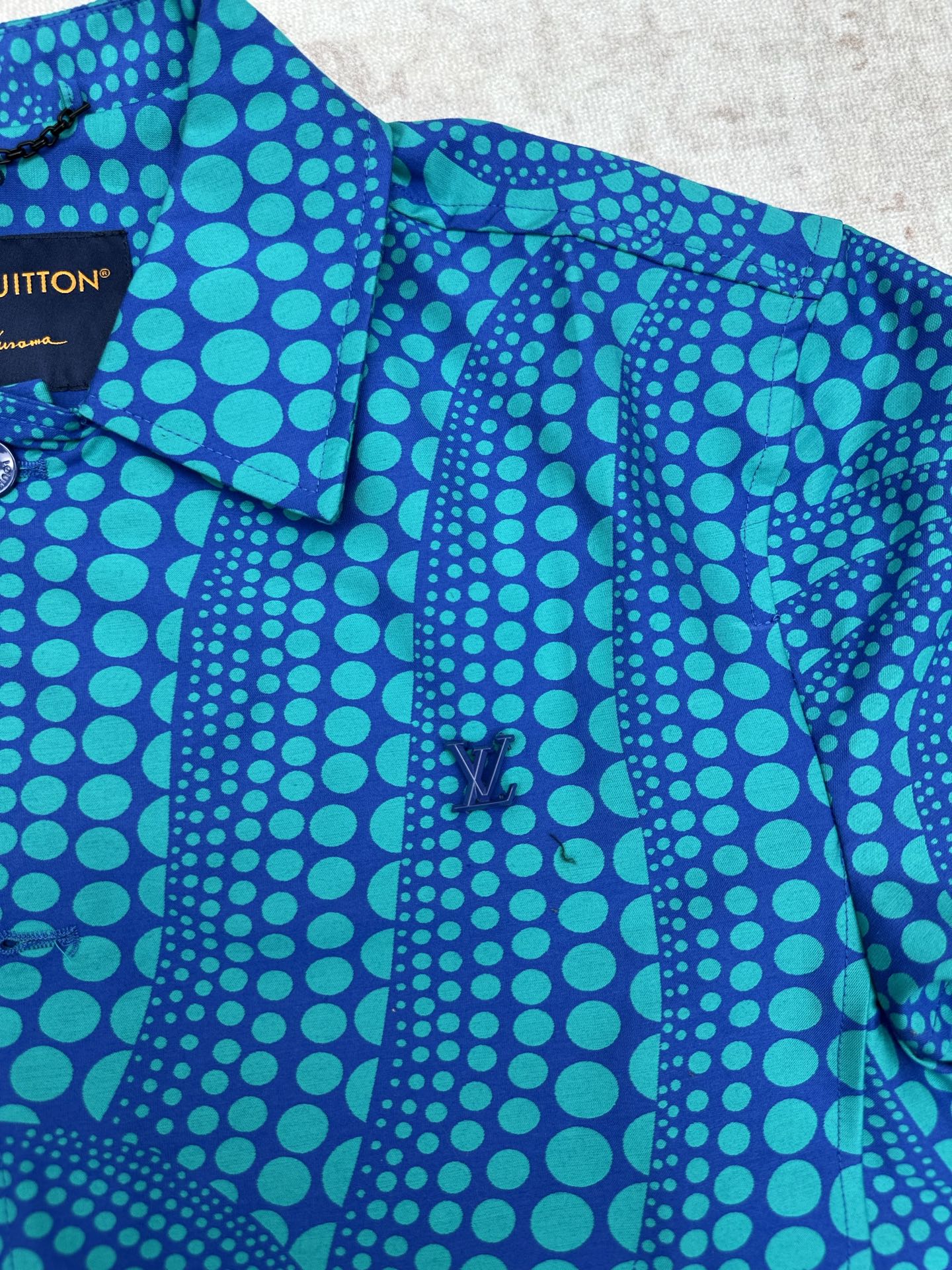 Blue long-sleeve button-up shirt with teal dot pattern and button placket
