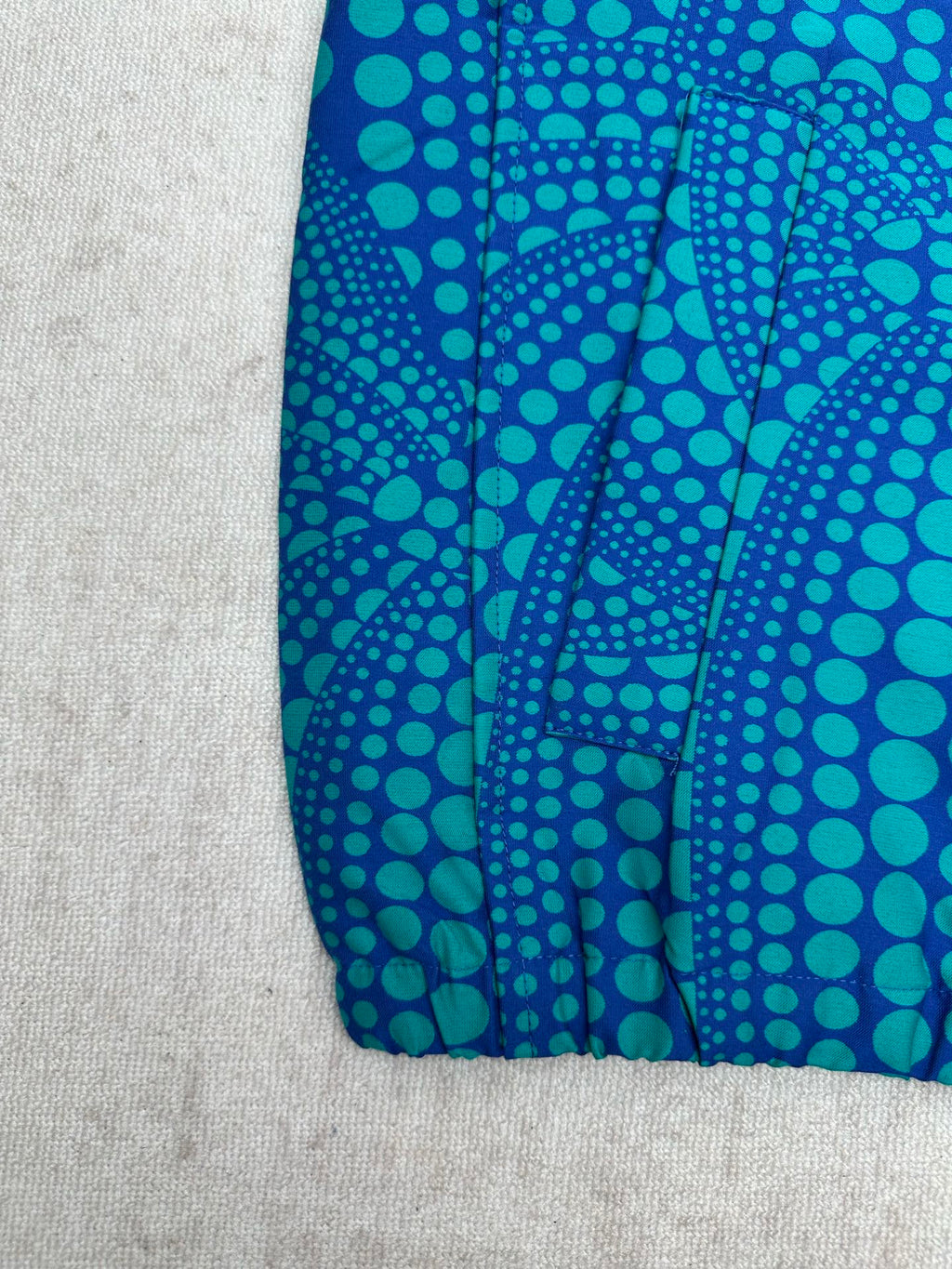 Blue long-sleeve button-up shirt with teal dot pattern and gathered hem