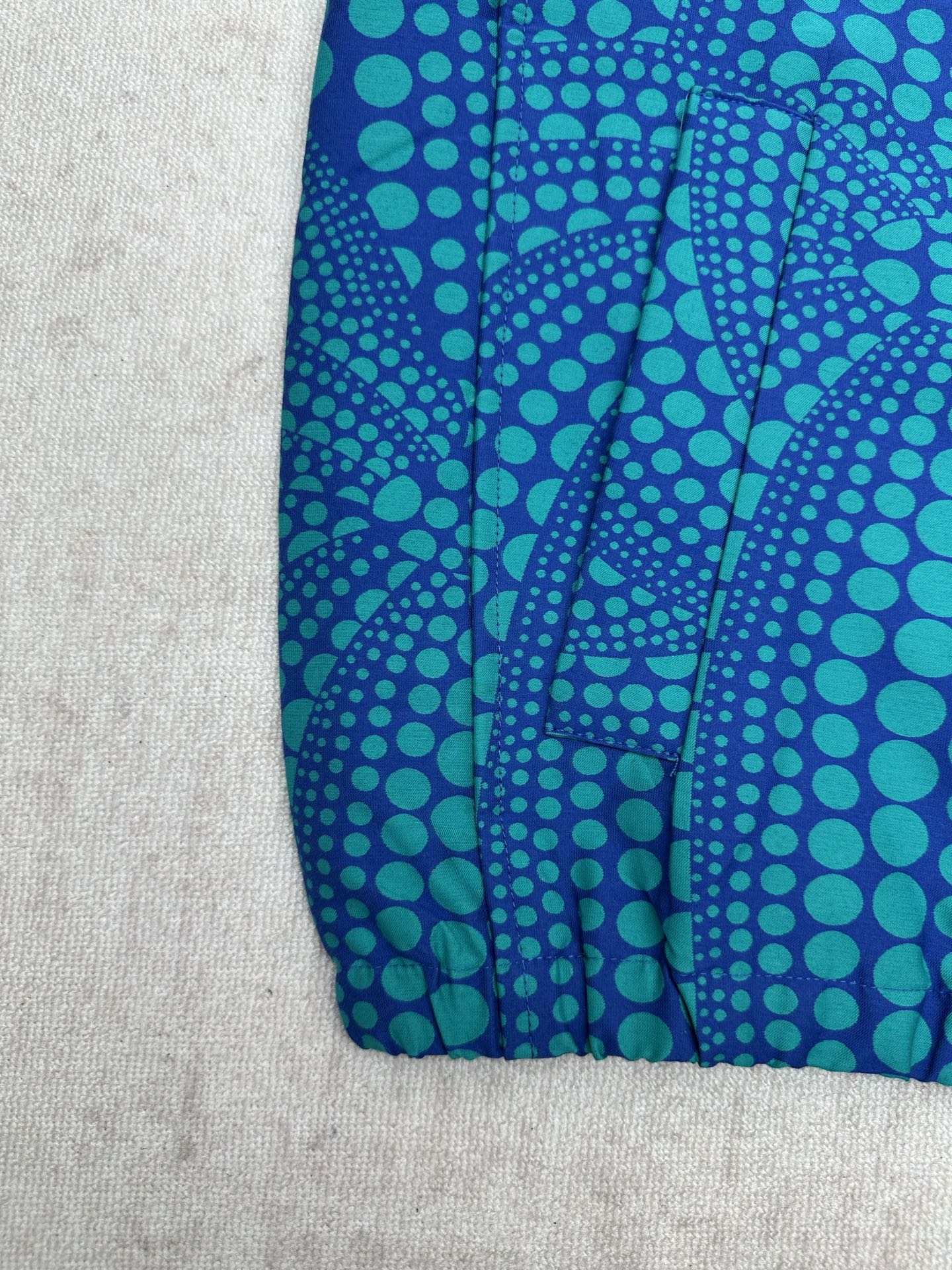 Blue long-sleeve button-up shirt with teal dot pattern and gathered hem