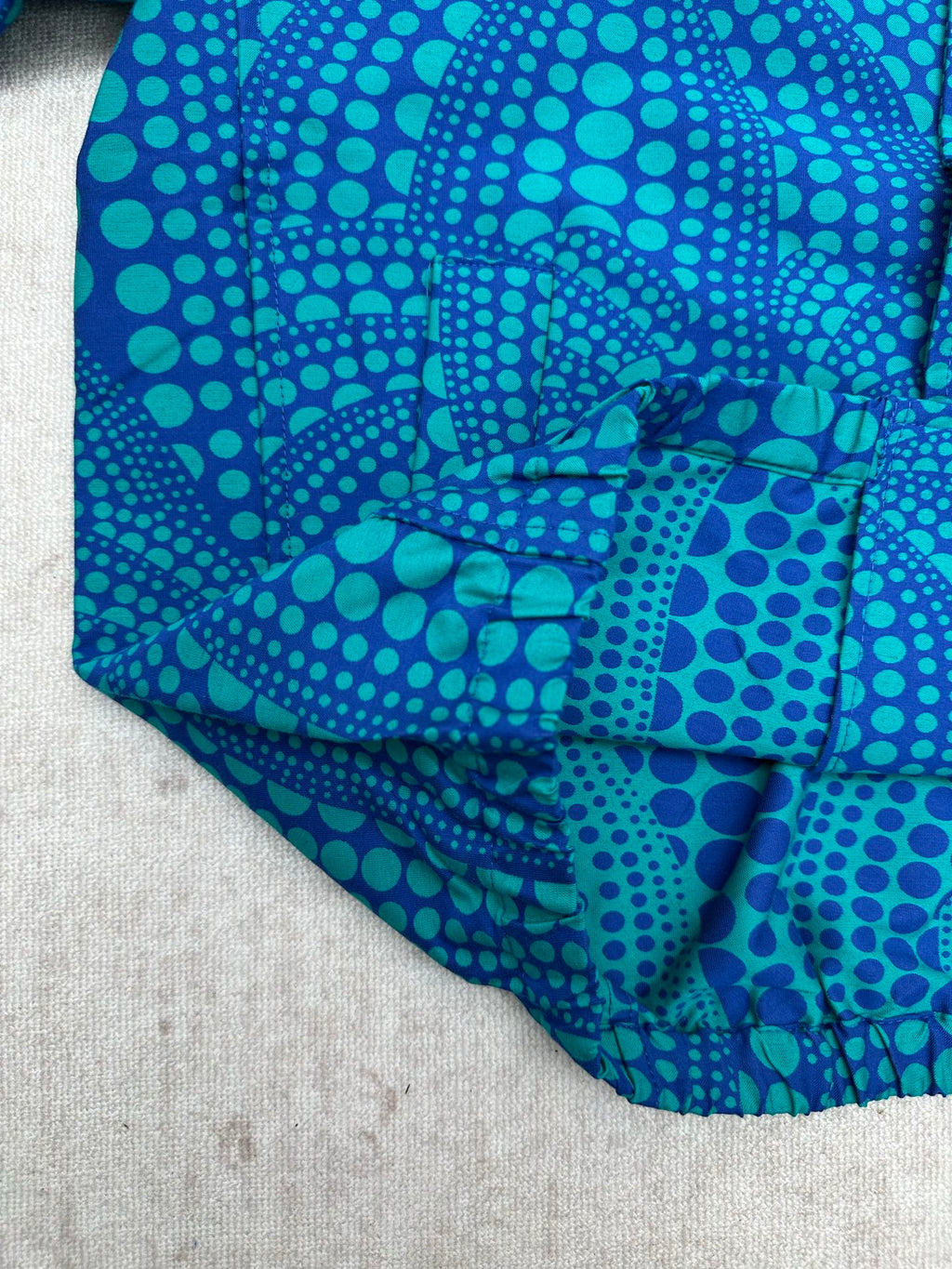 Blue long-sleeve button-up shirt with teal dot pattern, cuff and hem