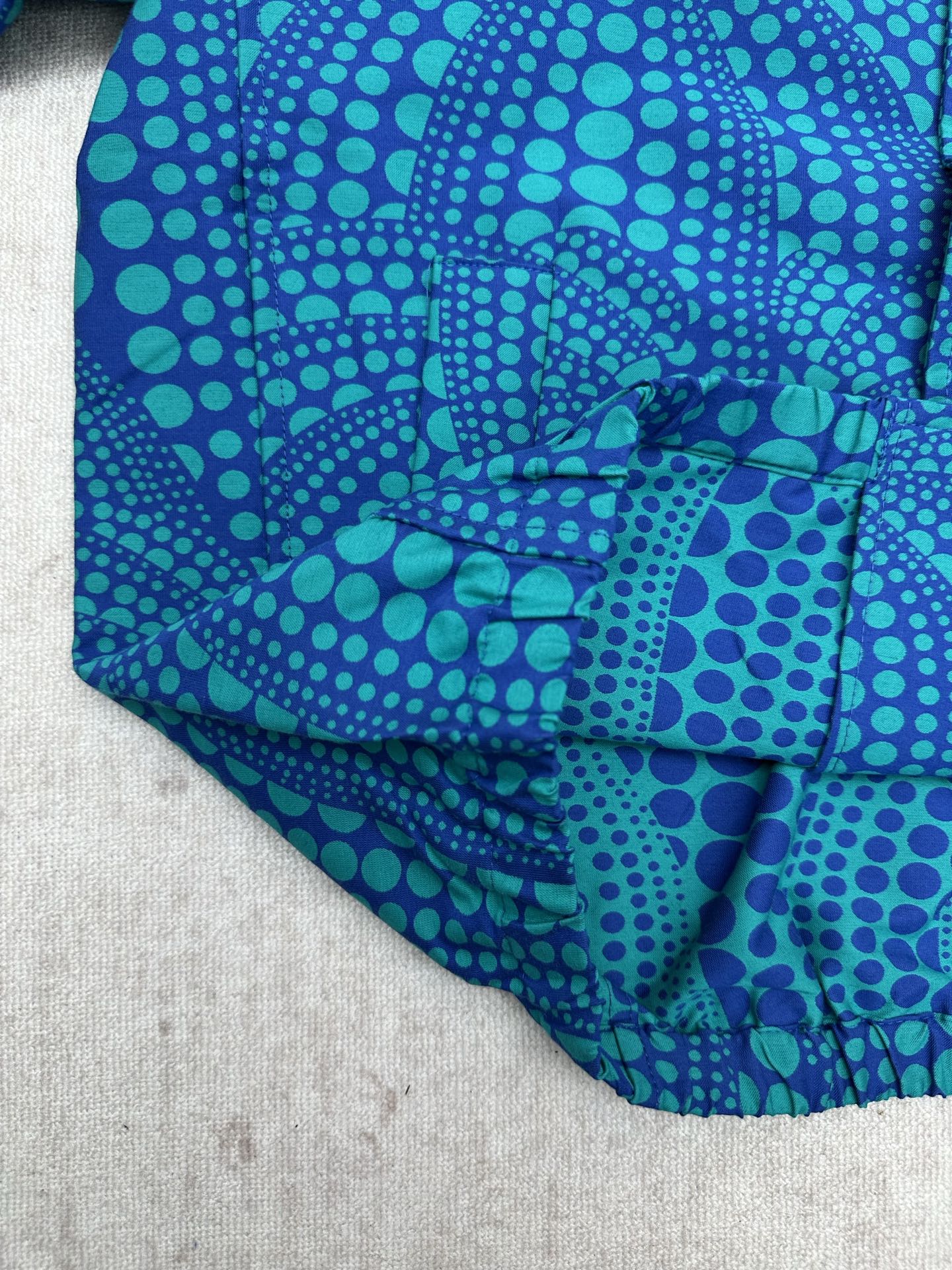Blue long-sleeve button-up shirt with teal dot pattern, cuff and hem