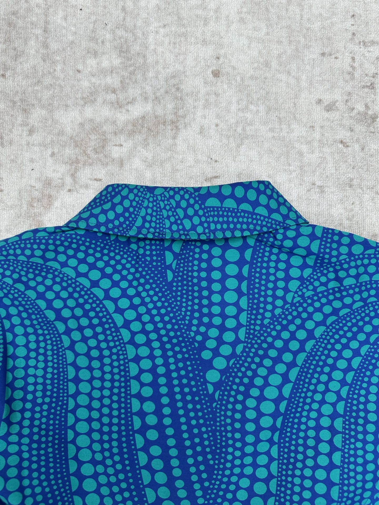 Blue long-sleeve button-up shirt collar with teal dot pattern