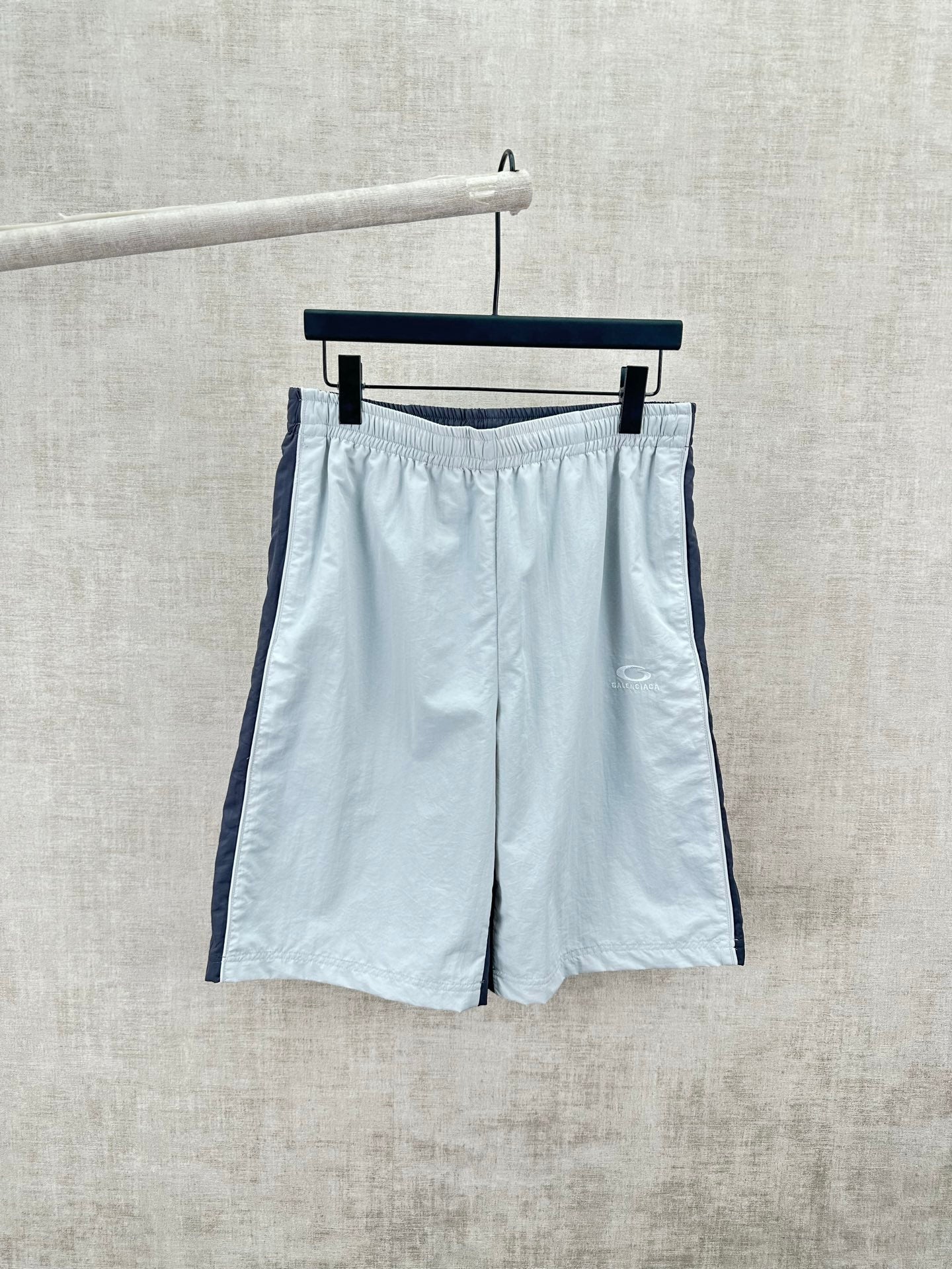 Light blue shorts with elastic waistband and dark side stripe, front view.
