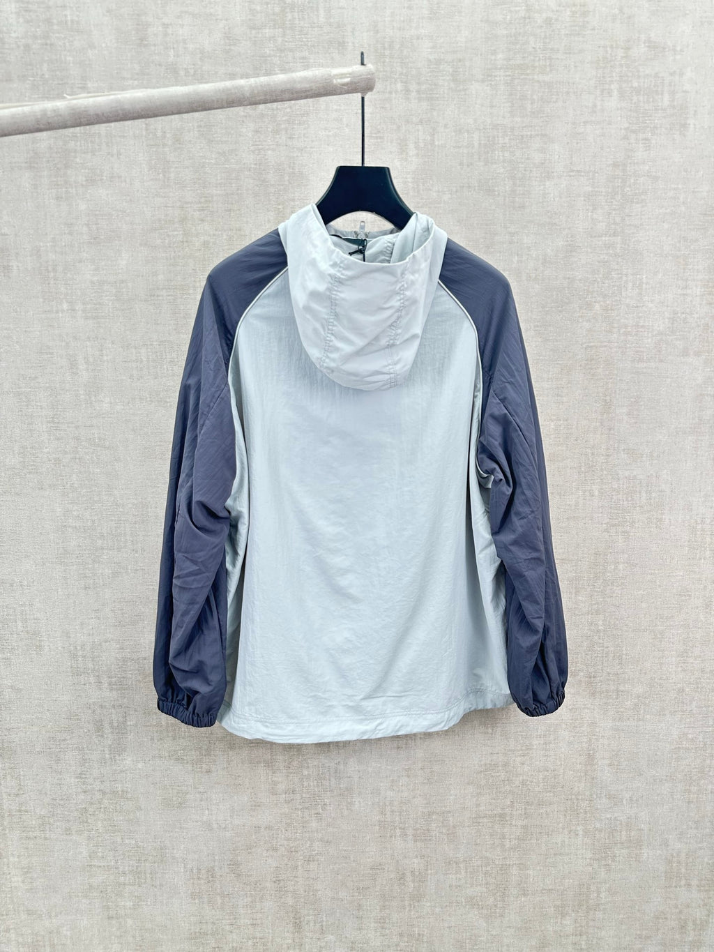 Light blue hooded wind jacket with high neck, navy sleeves, relaxed fit