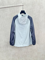Light blue hooded wind jacket with high neck, navy sleeves, relaxed fit