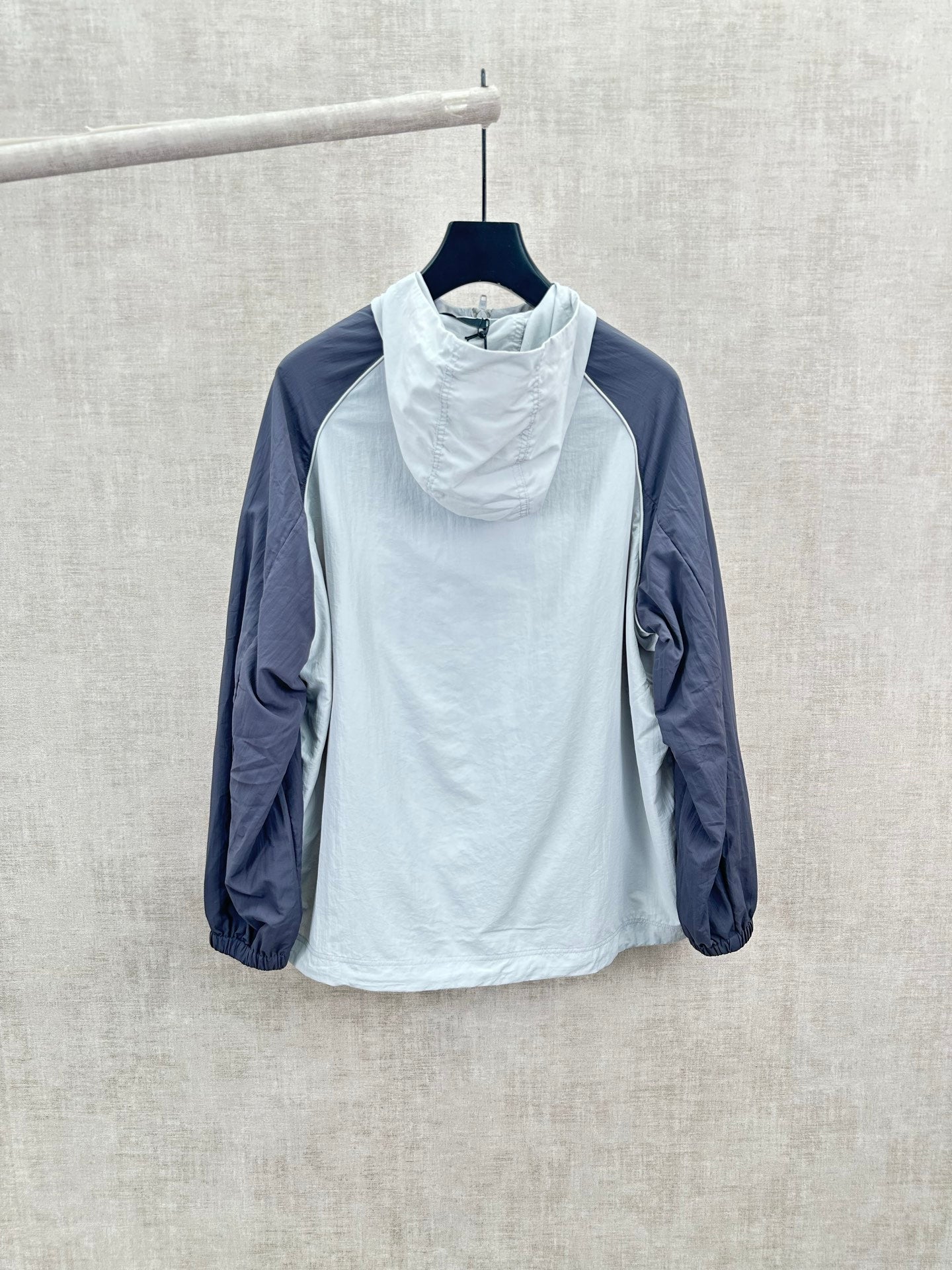 Light blue hooded wind jacket with high neck, navy sleeves, relaxed fit