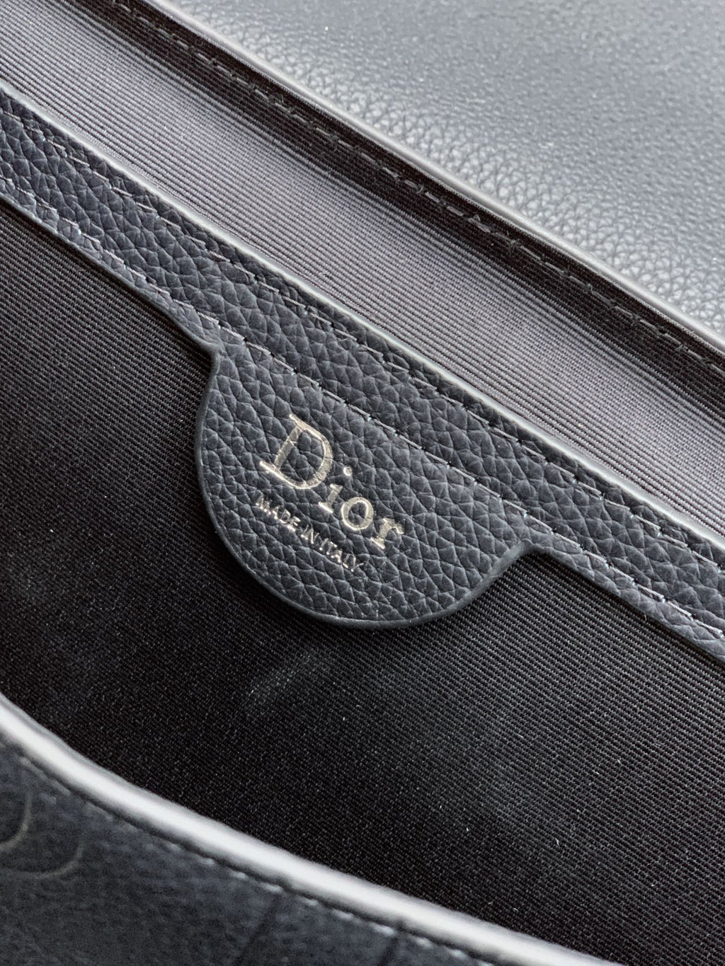 Close-up of navy Dior logo on flap pocket inside the crossbody bag