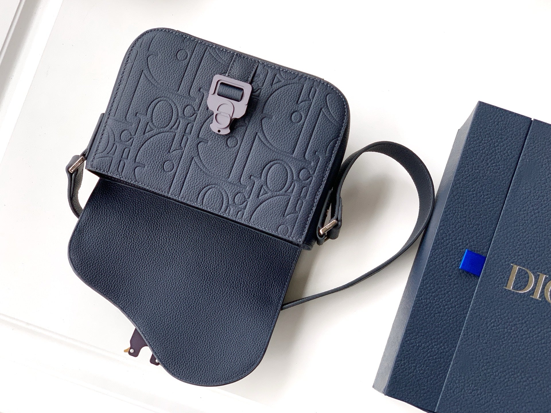 Navy crossbody bag with embossed front, chain strap, and flap pocket