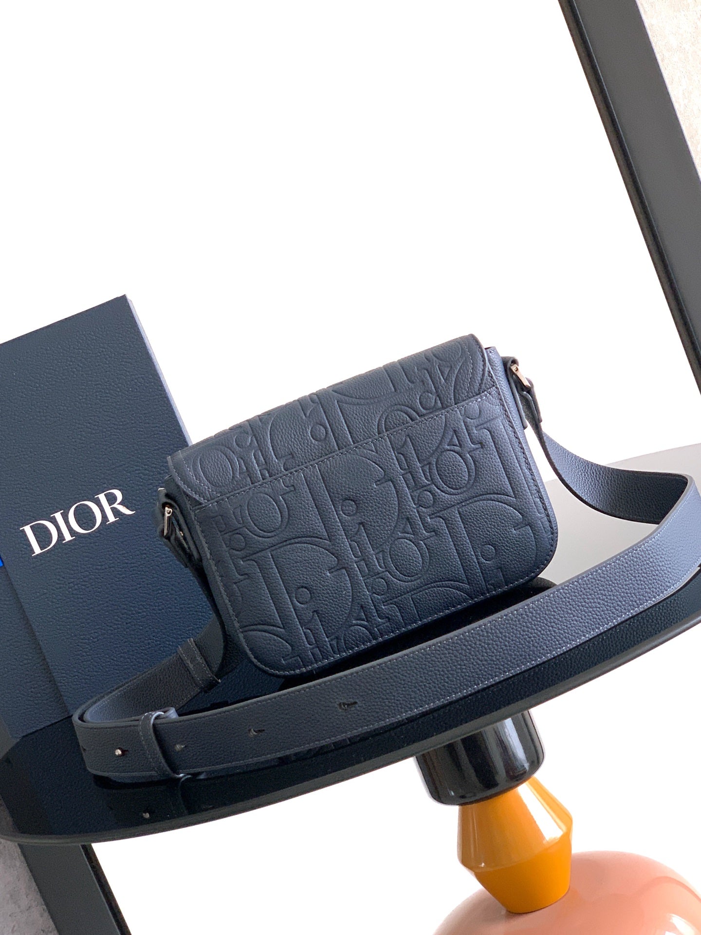 Navy crossbody bag with embossed logo flap and wide adjustable shoulder strap