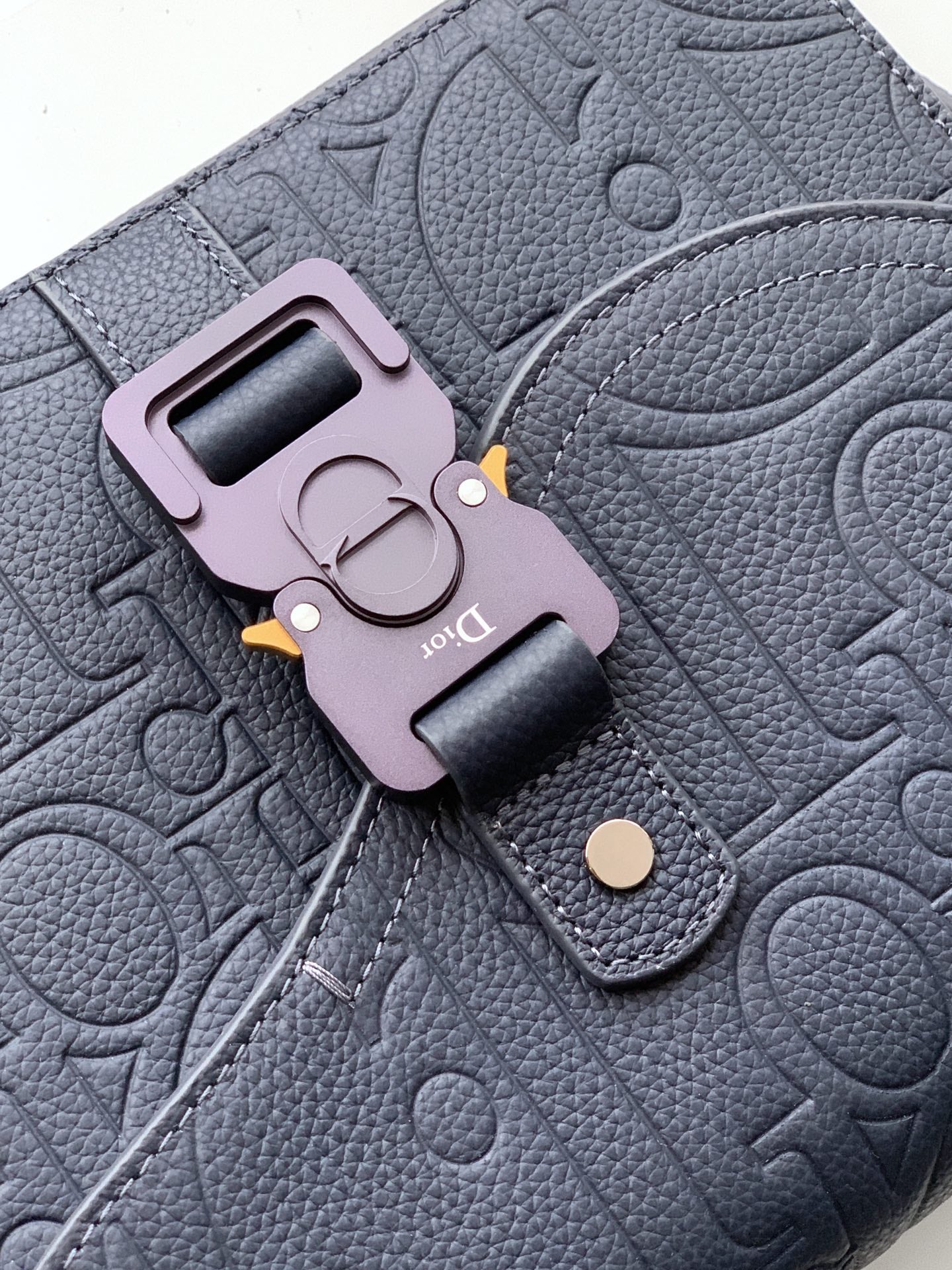 Embossed navy crossbody bag with pink keyring charm and metal clasp