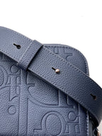 Close-up of navy crossbody strap with snap button and embossed trim
