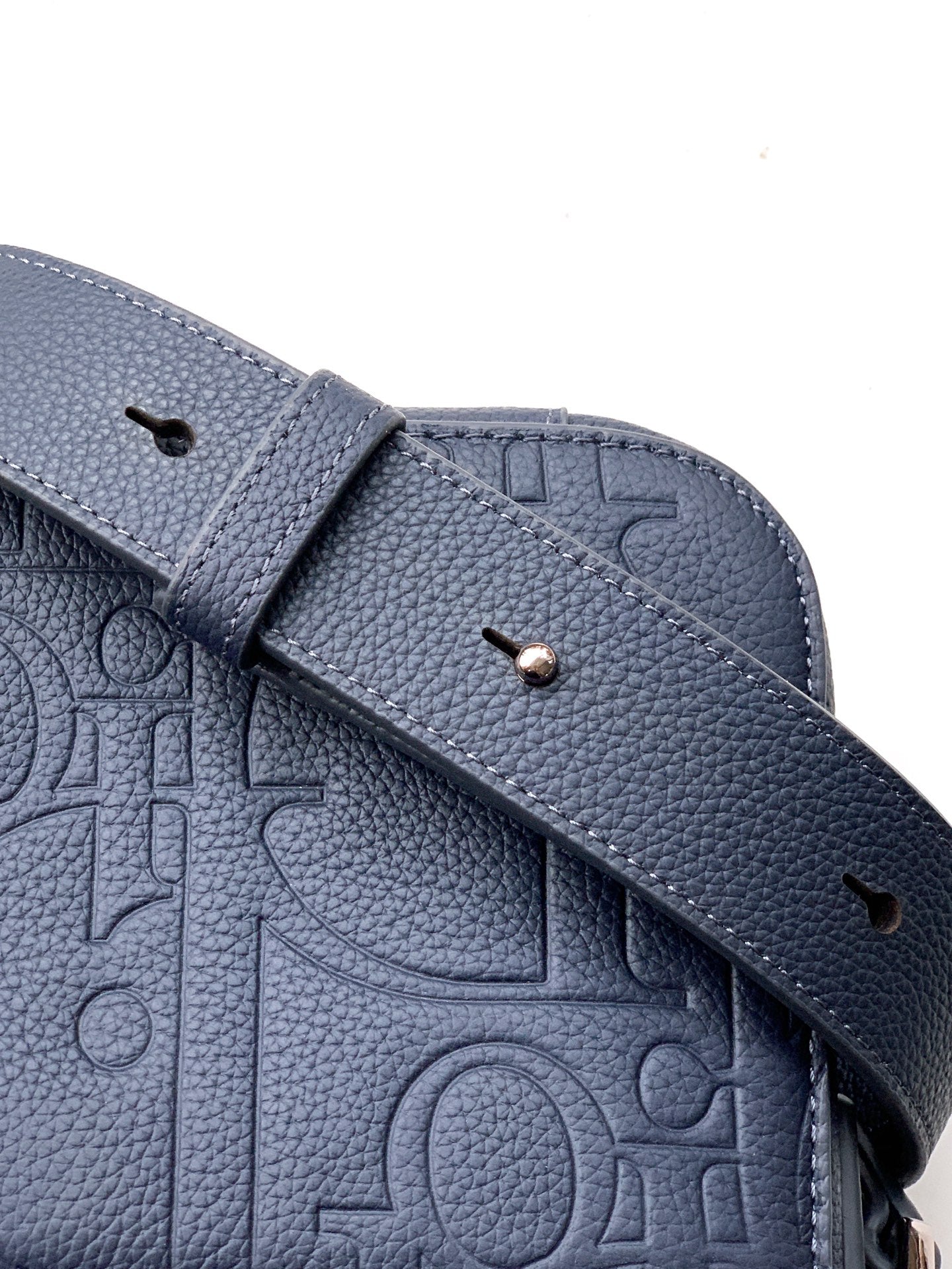 Close-up of navy crossbody strap with snap button and embossed trim