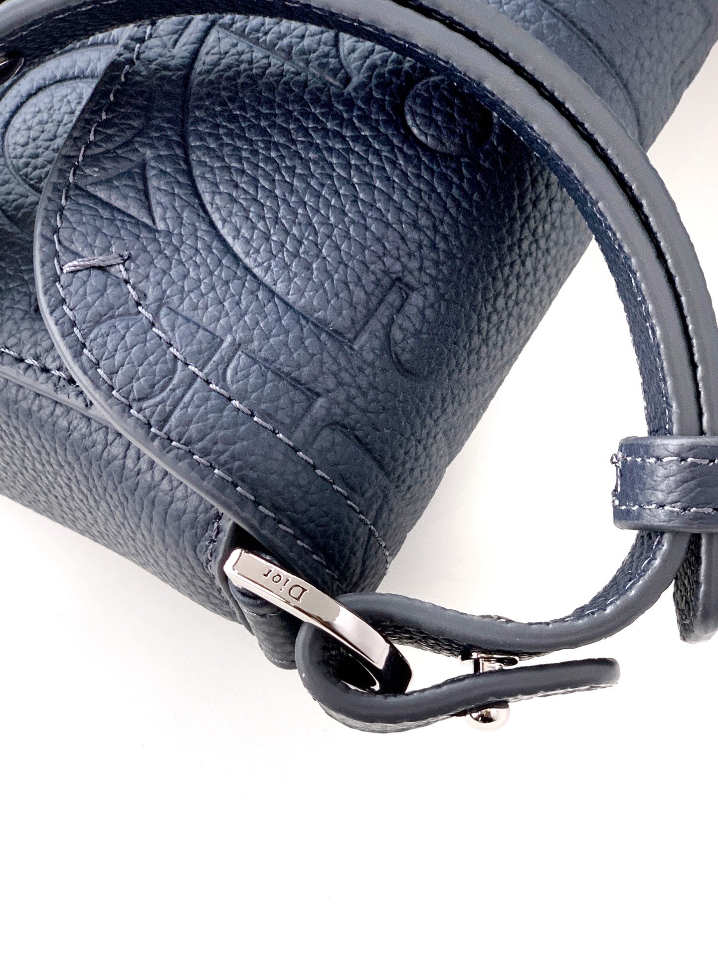 Navy blue Dior bag close-up of leather strap with metal ring and hardware