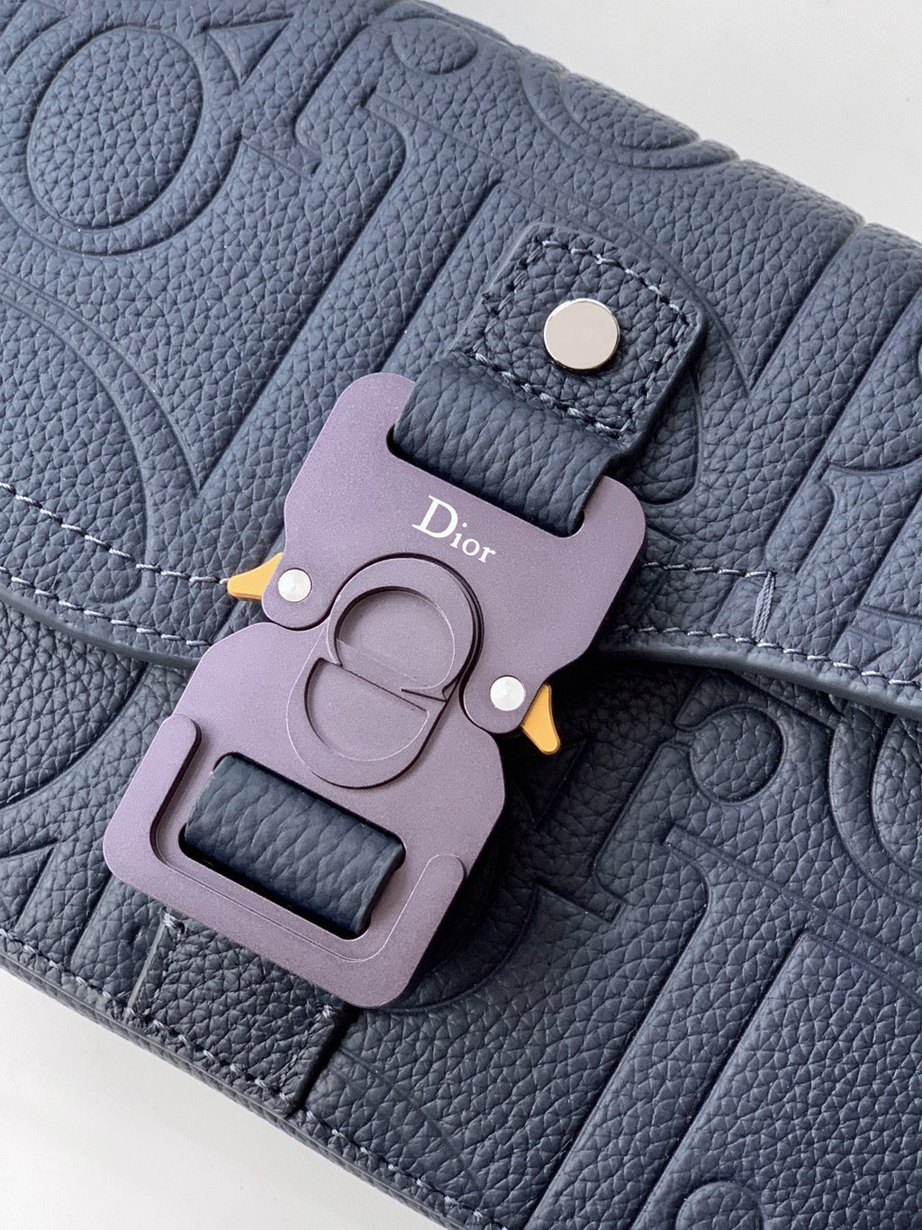 Navy blue Dior bag close-up of logo charm and metal front clasp