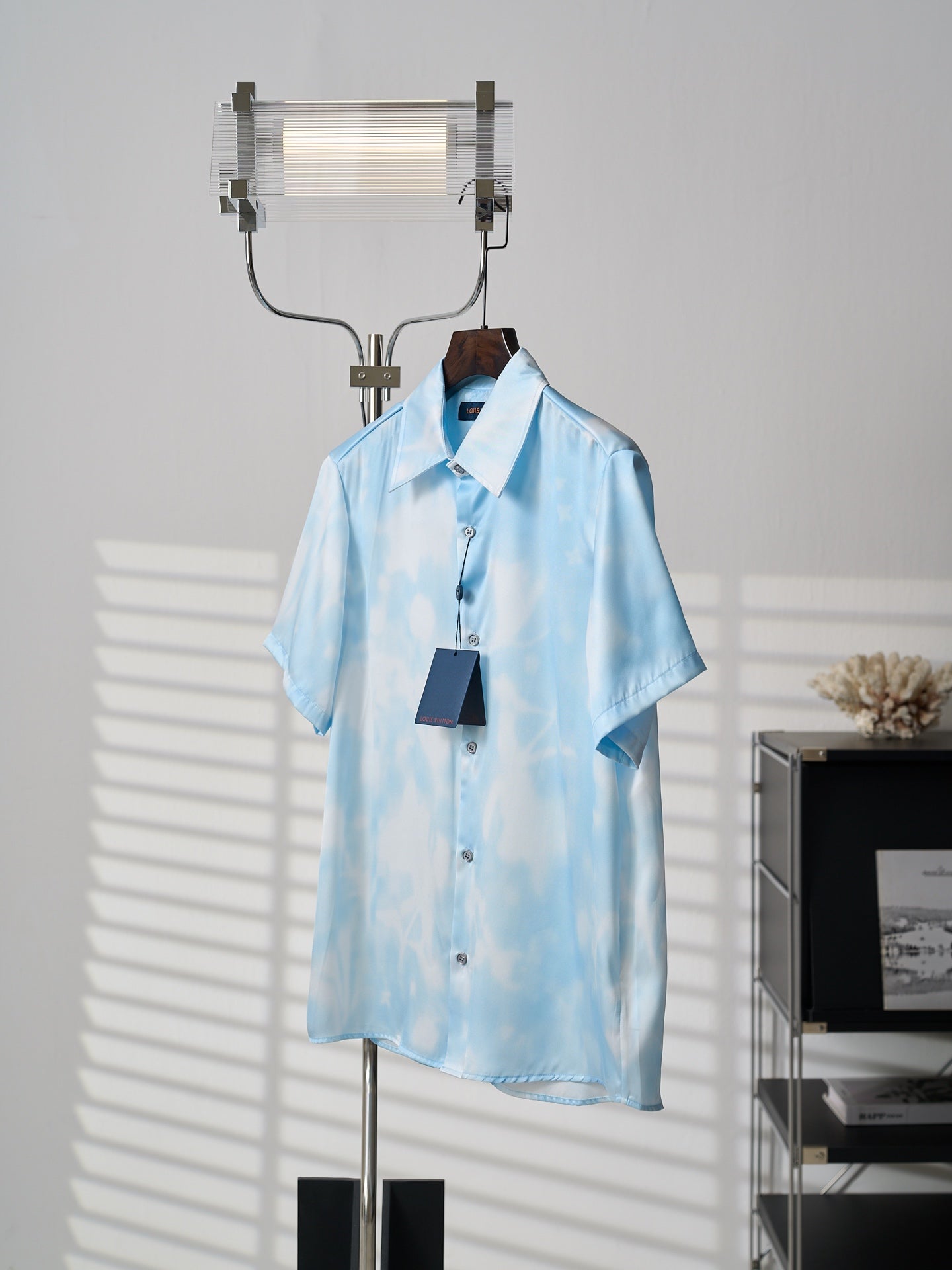 Light blue short-sleeve button-up shirt on hanger, button front with hanging tag