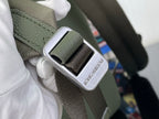 Louis Vuitton leather backpack strap buckle close-up with engraved LV mark, sage green.