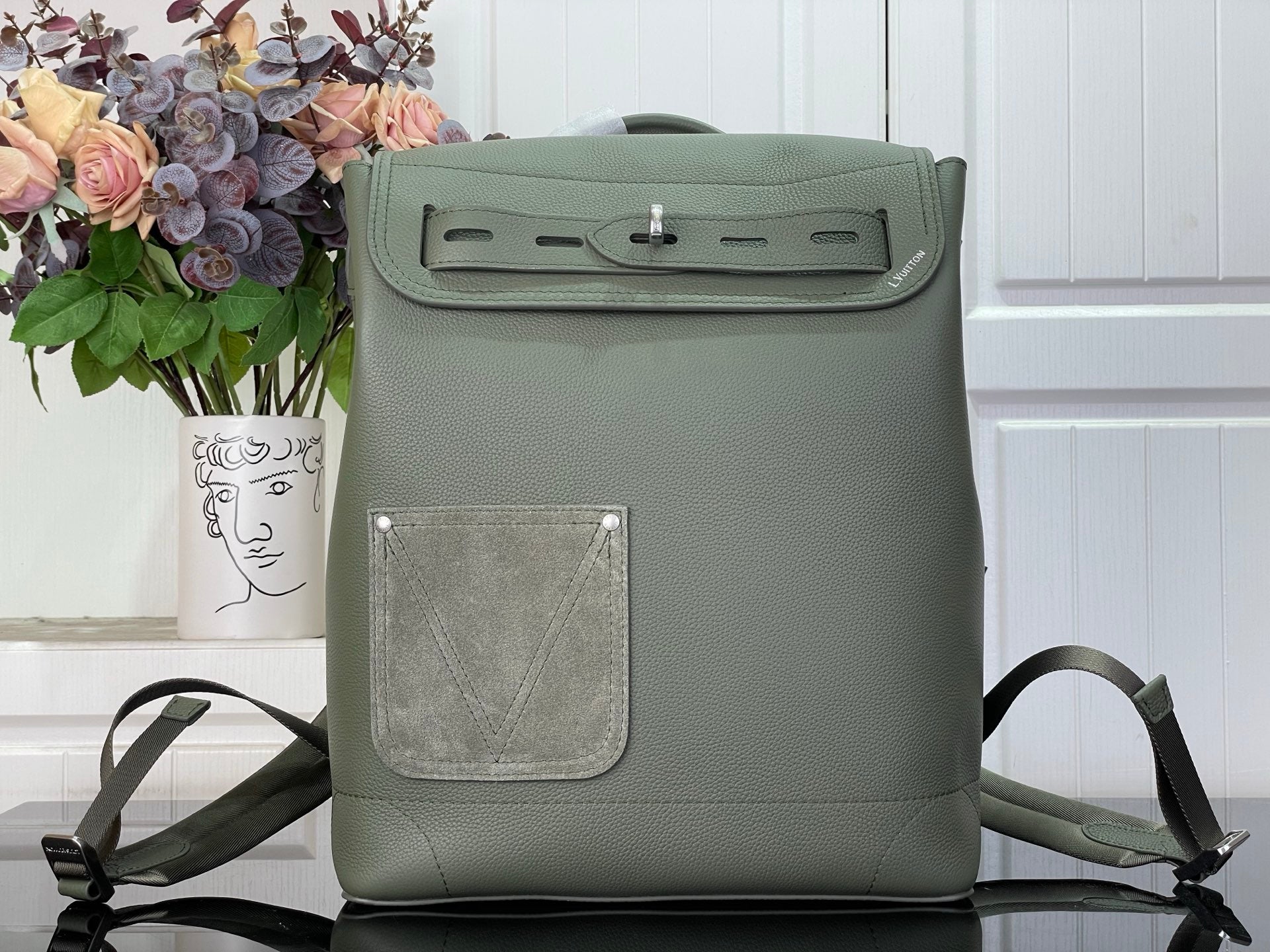 Louis Vuitton leather backpack with front flap and magnetic clasp, sage green.