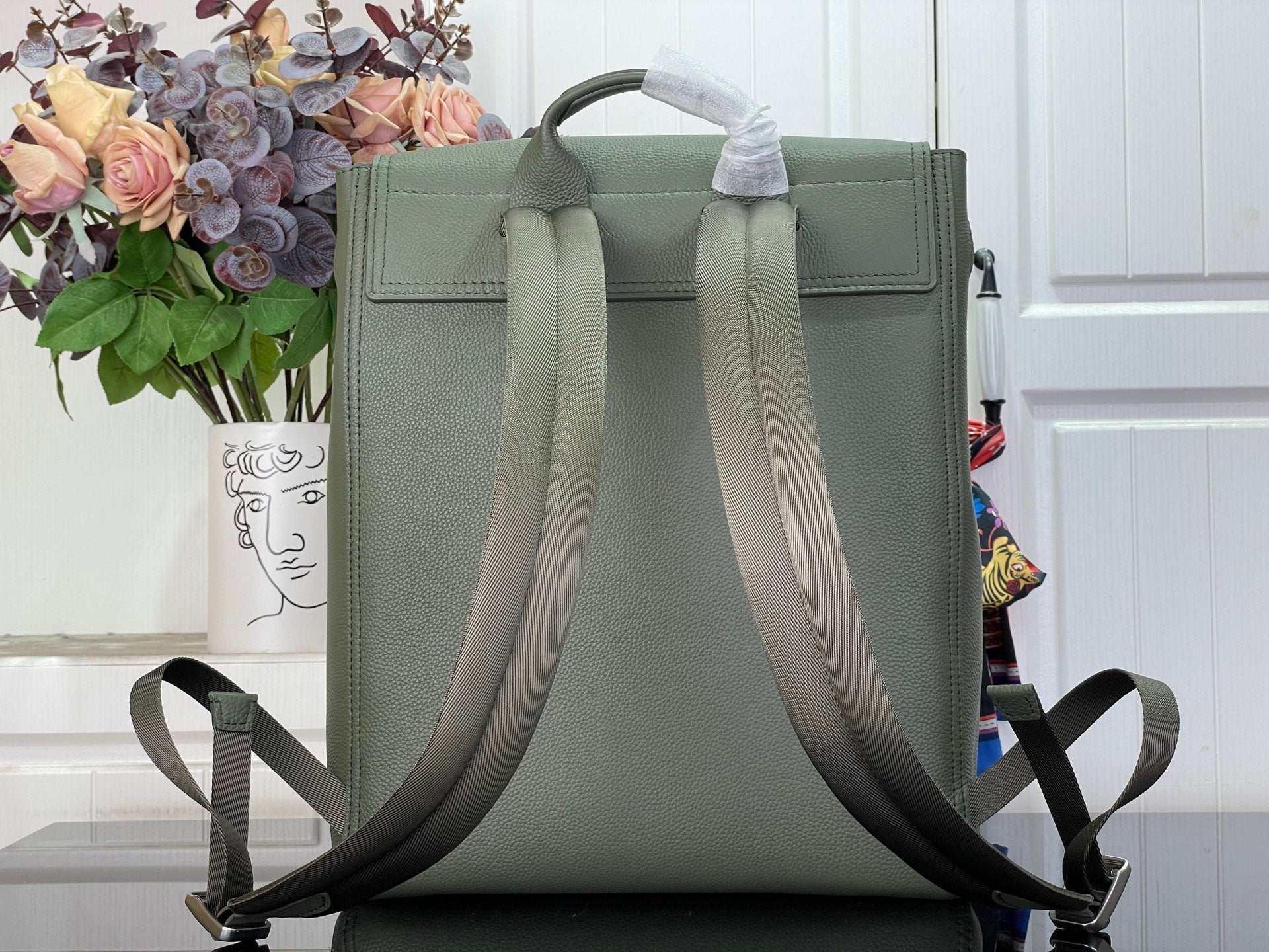 Louis Vuitton leather backpack back view with top handle and adjustable straps, sage green.
