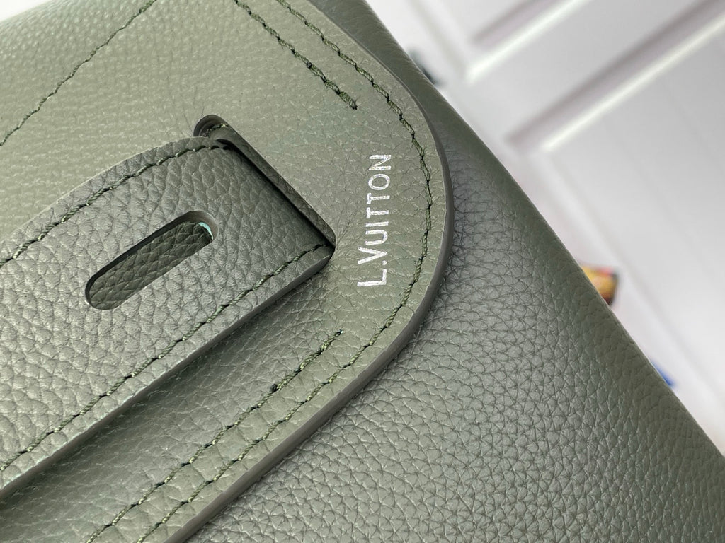 Louis Vuitton leather backpack strap adjuster close-up with embossed LV mark, sage green.