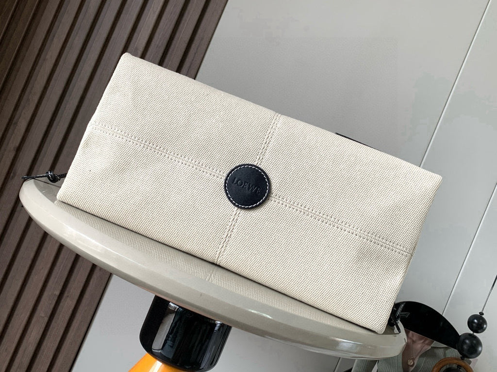 Cream canvas clutch pouch with dark snap button and round logo patch
