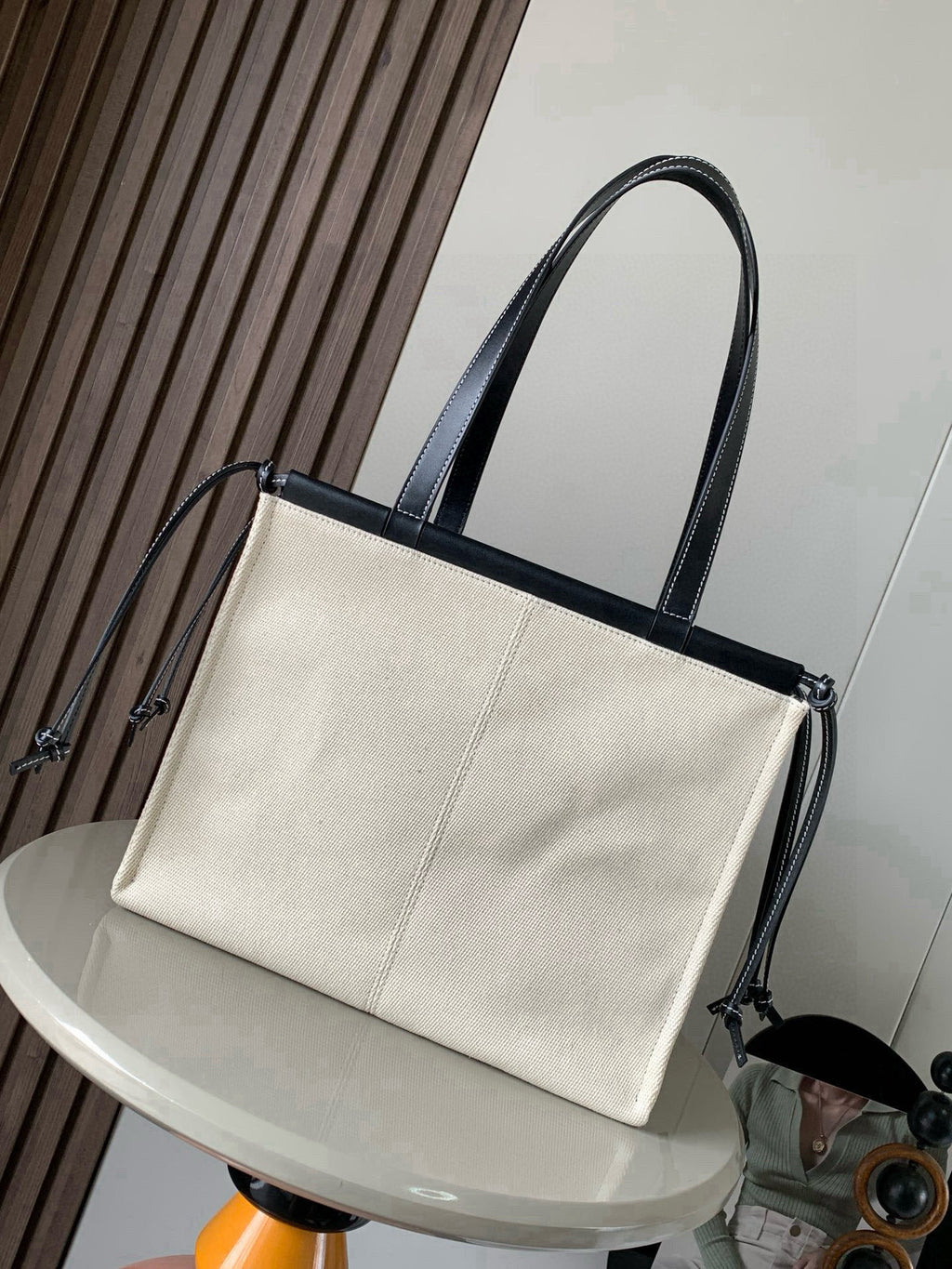Cream canvas tote bag with dark leather handles and side drawcord details