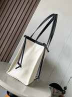 Cream canvas tote bag with dark leather straps and side drawstring cords