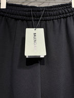 Black pants with hanging BALENCIAGA clothing tag at the waistband