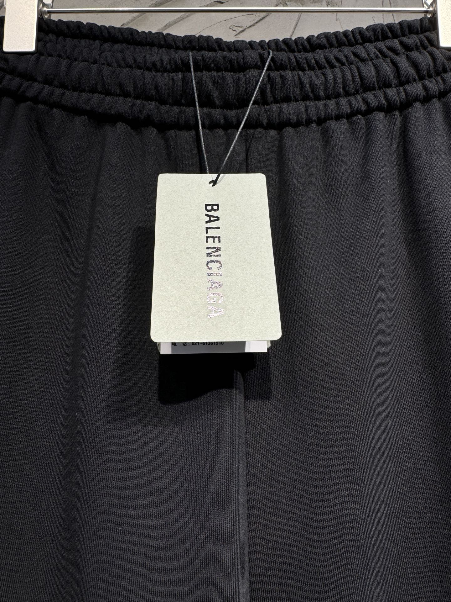 Black pants with hanging BALENCIAGA clothing tag at the waistband