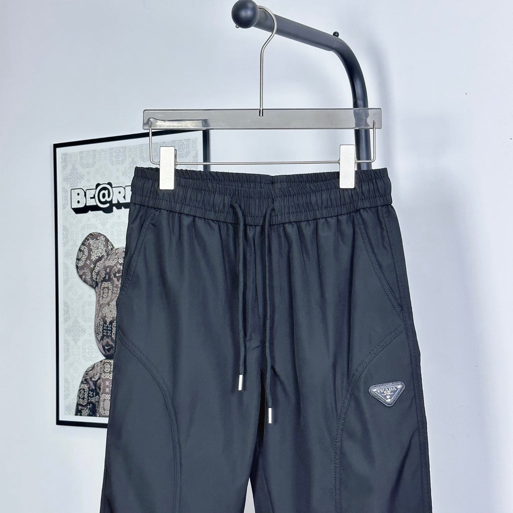 Prada track pants in dark navy with elastic waistband and drawstring; logo patch on leg