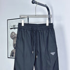 Prada track pants in dark navy with elastic waistband and drawstring; logo patch on leg