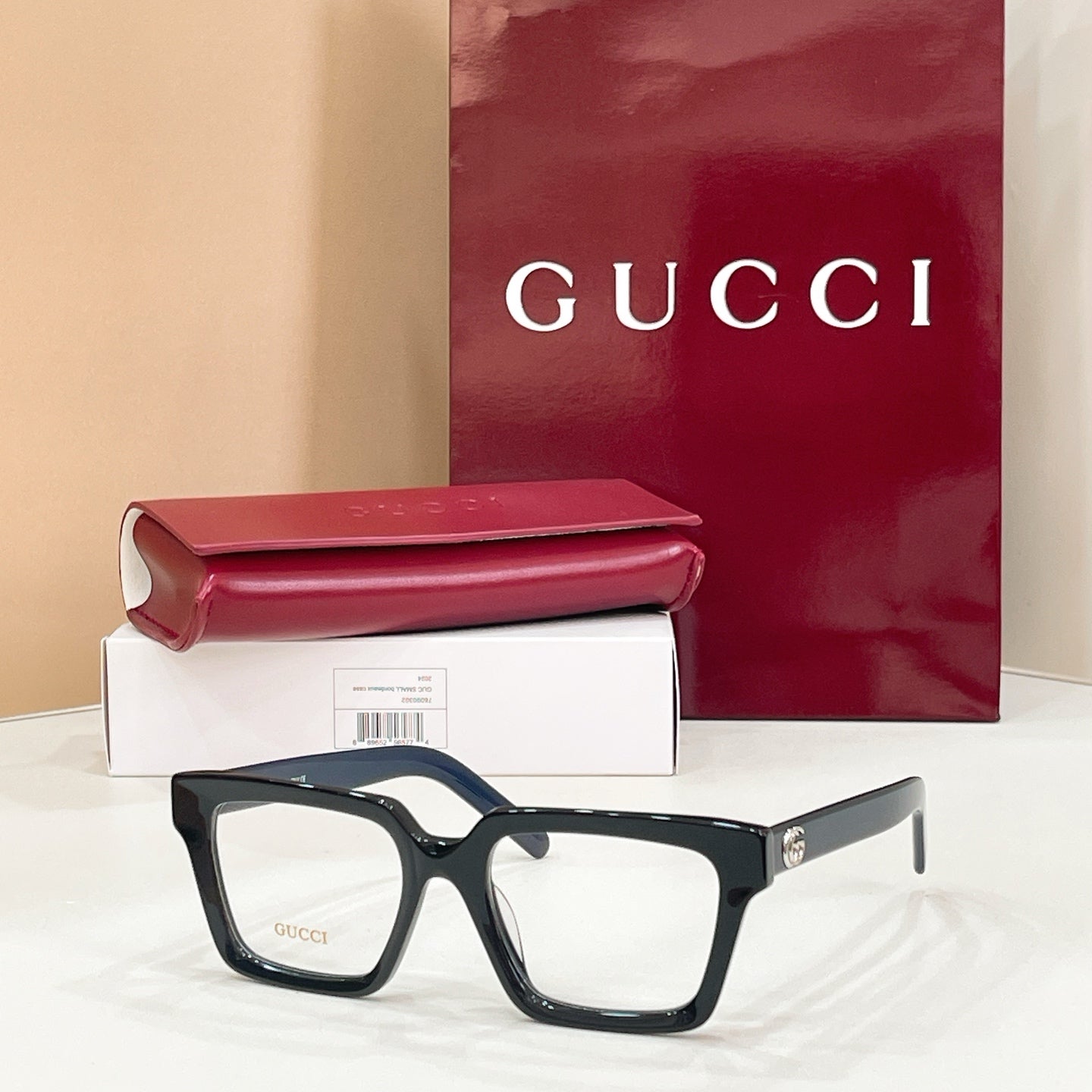 Rectangular eyeglasses with dark blue frame and clear lenses, gold-tone temple emblem