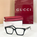 Rectangular eyeglasses with dark frame and light lenses, gold-tone temple logo detail
